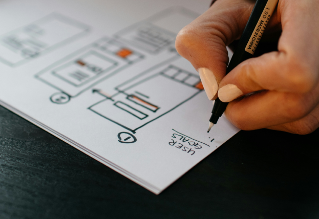 Image Description: A person sketching a website wireframe with a focus on user goals
